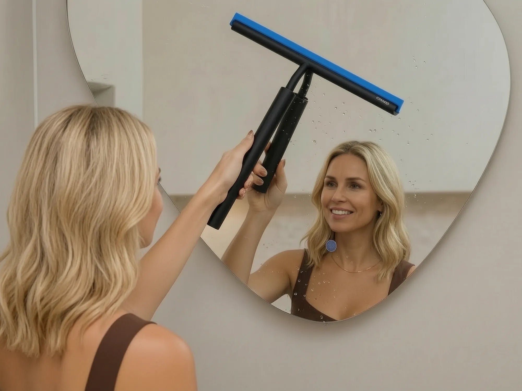 Vrouw wist een badkamerspiegel droog met een raamwisser